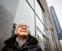 Ein älterer Mann mit weißen Haaren und Brille steht vor dem Bezirksamt Mitte