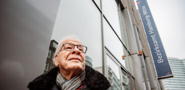 Ein älterer Mann mit weißen Haaren und Brille steht vor dem Bezirksamt Mitte