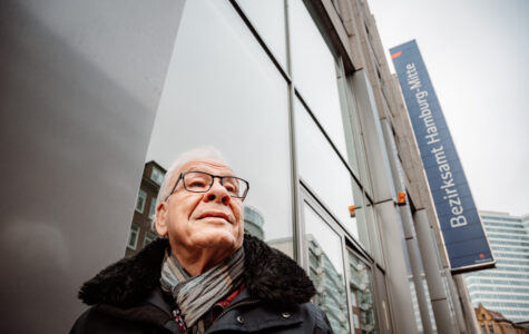 Ein älterer Mann mit weißen Haaren und Brille steht vor dem Bezirksamt Mitte