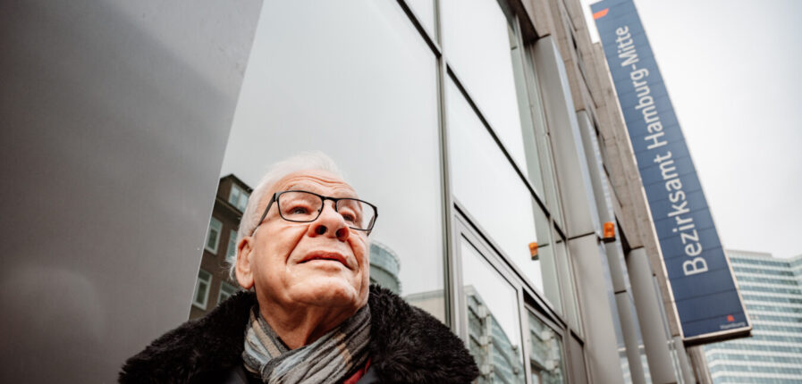 Ein älterer Mann mit weißen Haaren und Brille steht vor dem Bezirksamt Mitte