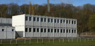 Weiße Container mit Fenstern stehen in einer Reihe auf einer Wiese