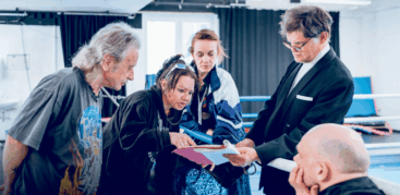 Eine Gruppe von Menschen steht um eine Mappe herum und diskutiert