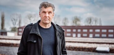 Ein Mann mit grauen Haaren und ernstem Blick steht auf dem Gelände der Gedenkstätte Neuengamme.