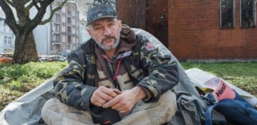 Ein Mann mit Tarnfleck-Jacke sitzt vor einem Igluzelt und schaut traurig in die Kamera.