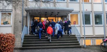 Eine Menschengruppe geht auf die Tür der Unterkunft zu.