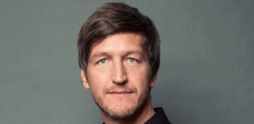 Porträtfoto von einem dunkelblonden Mann im schwarzen Hemd