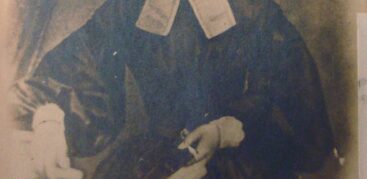 Ein altes schwarz-weiß-Foto von einer Frau mit gelockten Haaren