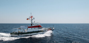 Ein Schiff fährt durch das Meer. An Deck ist ein Banner mit der Aufschrift "LeaveNoOneToDie" angebracht.