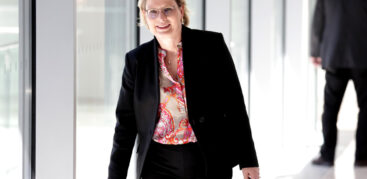 Eine Frau mit bunter Bluse und schwarzem Jackett