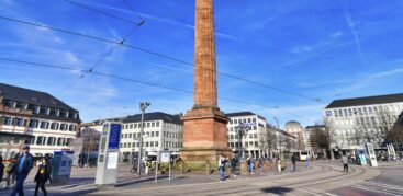 Ein Platz mit einer großen Säule in der Mitte, über den Menschen spazieren