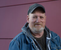 Ein Mann mit schwarzem Käppi und Jeansjacke