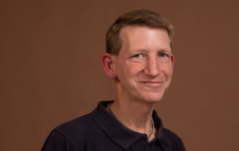 Ein blonder Mann im Polohemd lacht in die Kamera