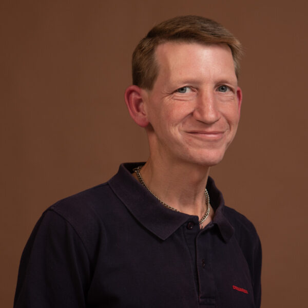 Ein blonder Mann im Polohemd lacht in die Kamera