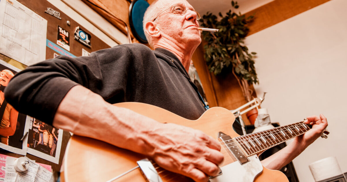 Ein Mann spielt Gitarre und raucht