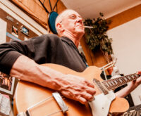 Ein Mann spielt Gitarre und raucht