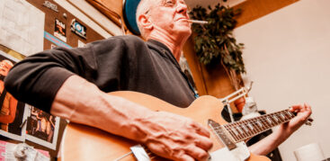 Ein Mann spielt Gitarre und raucht