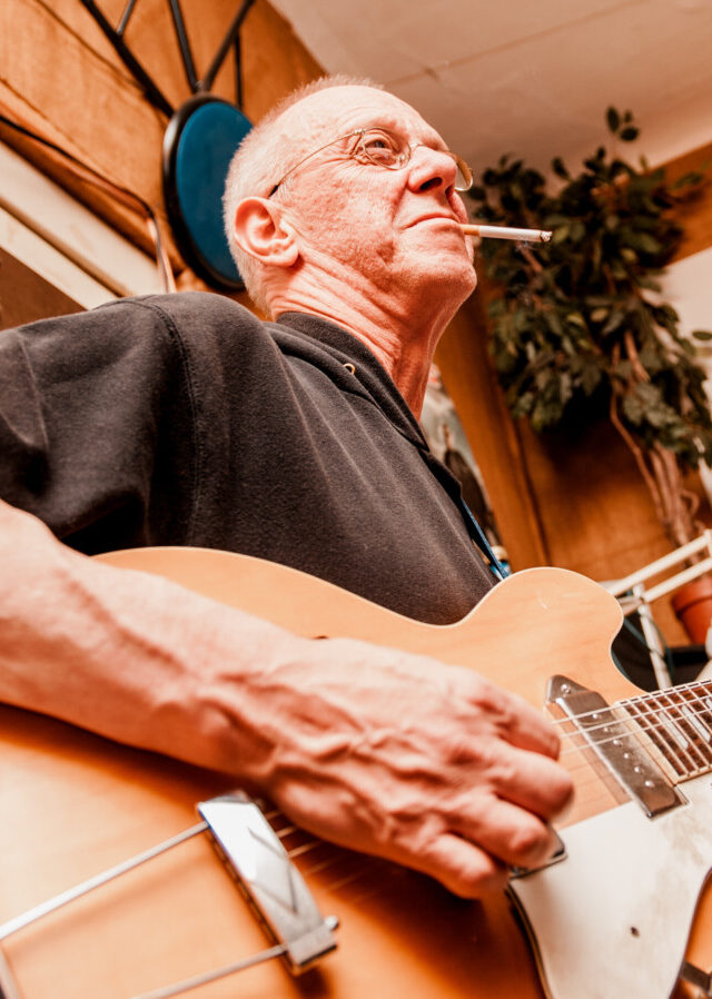 Ein Mann spielt Gitarre und raucht