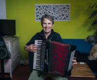 Eine Frau mit kurzen Haaren spielt auf einem Akkordeon