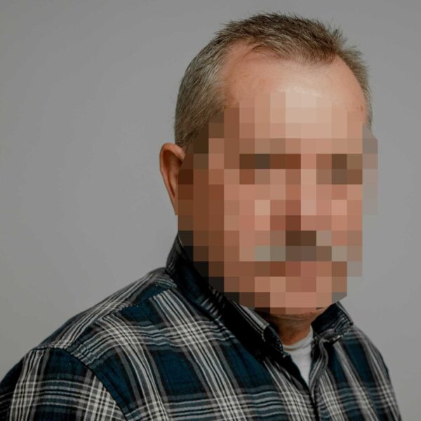 Foto von einem grauhaarigen Mann im Flanellhemd, das Gesicht ist verpixelt