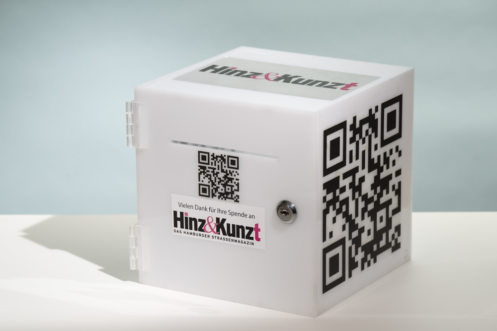 Ein weißer Plastikwürfel mit Hinz&Kunzt-Logo und QR-Code