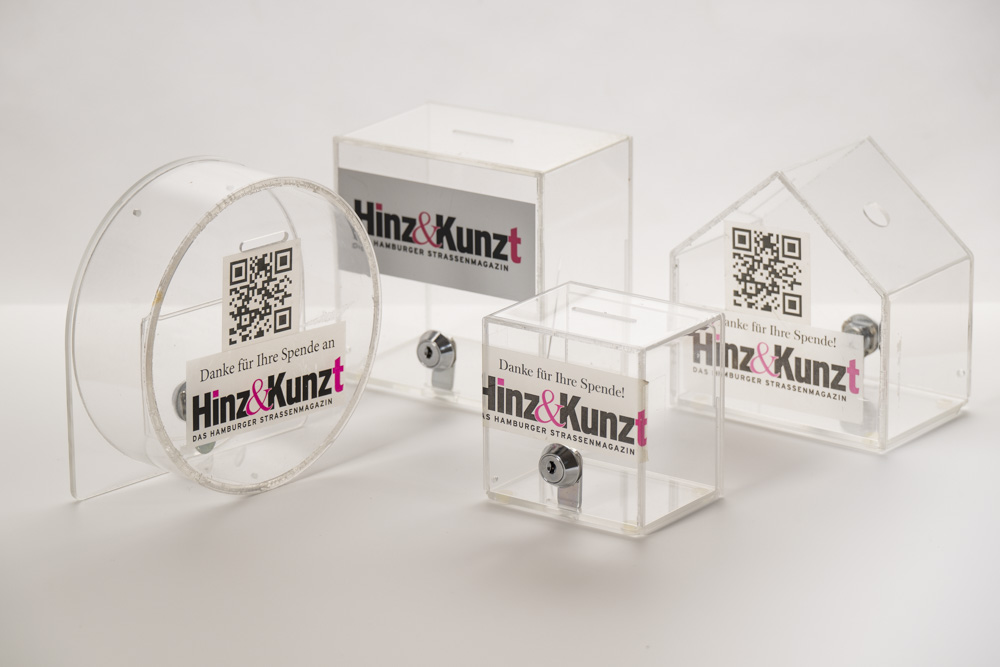 durchsichtige Objekte zum Geldeinwerfen mit Hinnz&Kunzt-Logo und QR-Code