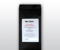Das Bild zeigt eine schwarze Kaffeeverpackung mit einem weißen Etikett in der Mitte. Auf dem Etikett steht in roter und schwarzer Schrift "Hinz & Kunzt Espresso ¡DESOACITO!". Darunter sind Details zum Kaffee aufgeführt