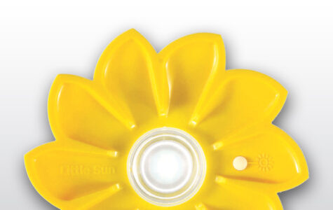 Das gezeigte Bild ist eine gelbe, blumenförmige Solarleuchte mit einer zentralen, transparenten Kapsel, die ein Leuchtmittel enthält, und einem kleinen, runden Schalter mit Sonnensymbol und dem Namen „little sun“ auf einem der Blütenblätter. Ein weiser Druckknopf ist direkt daneben.