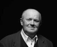 Ein Mann mit Glatze, weißem Hemd und Sakko