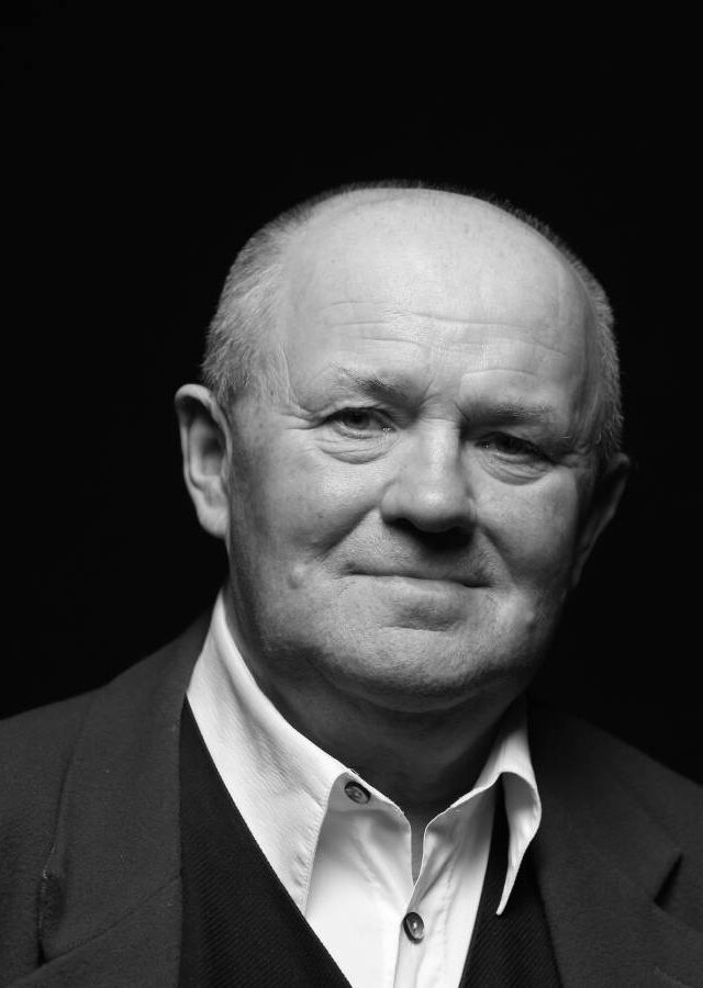 Ein Mann mit Glatze, weißem Hemd und Sakko