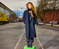 Eine Frau mit lockigen Haaren steht auf einer grünen Kiste