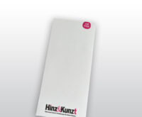 Das Bild zeigt einen weißen rechteckigen Notizblock. Oben rechts ein kleiner magentafarbene Kreis mit dem Text: „seit 1993“. Am unteren Rand ist das Hinz&Kunzt Logo aufgedruckt