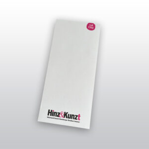 Das Bild zeigt einen weißen rechteckigen Notizblock. Oben rechts ein kleiner magentafarbene Kreis mit dem Text: „seit 1993“. Am unteren Rand ist das Hinz&Kunzt Logo aufgedruckt