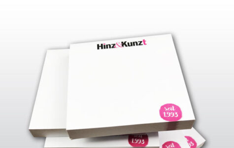 Das Bild zeigt fünf weiße aufgetürmte Hafttotizblöcke mit dem Hinz&Kinzt Logo und einem kleinen Kreis in Magenta in dem das Gründungsjahr 1993 steht
