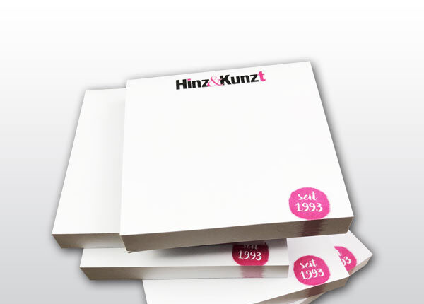 Das Bild zeigt fünf weiße aufgetürmte Hafttotizblöcke mit dem Hinz&Kinzt Logo und einem kleinen Kreis in Magenta in dem das Gründungsjahr 1993 steht