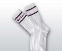 Das Bild zeigt ein Paar weiße Socken. Sie haben schwarze und magenta Streifen am Bund und tragen den Schriftzug "Hinz&Kunzt".