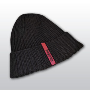 Die Abbildung zeigt eine dunkelblaue Strickmütze mit einem magentafarbenen Etikett, auf dem in schwarzer Schrift "Hinz&Kunzt" steht.