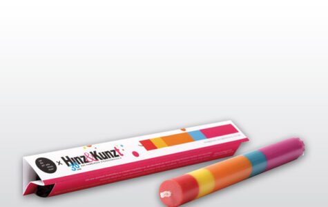 Das Bild zeigt eine mehrfarbige Stabkerze in verschiedenen horizontalen Farbschichten gestaltet, darunter Rot, Gelb, Orange, Türkis und Pink.