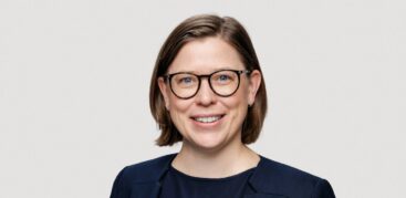 Eine Frau in dunkelblauem Sacko lächelt freundlich in die Kamera