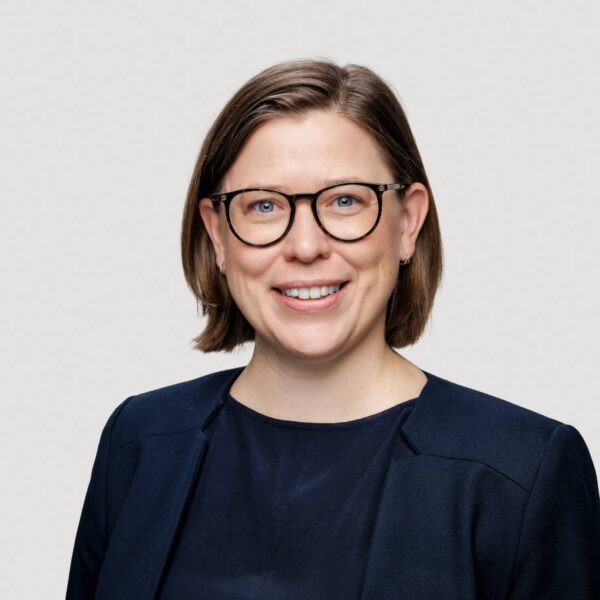 Eine Frau in dunkelblauem Sacko lächelt freundlich in die Kamera