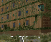 Ein holzvertäfeltes Haus mit viel Grün an der Fassade, darauf die Aufschrift "Una casa per tutti"