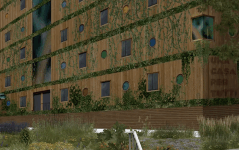 Ein holzvertäfeltes Haus mit viel Grün an der Fassade, darauf die Aufschrift "Una casa per tutti"