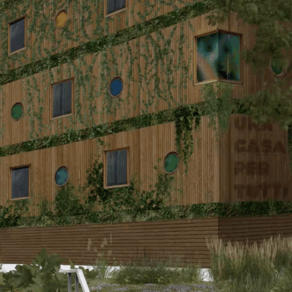 Ein holzvertäfeltes Haus mit viel Grün an der Fassade, darauf die Aufschrift "Una casa per tutti"