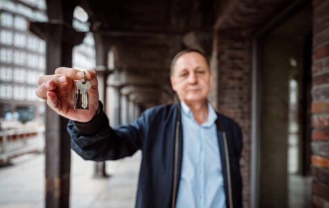 Ein Mann im blauen Hemd zeigt einen Wohnungsschlüssel in die Kamera