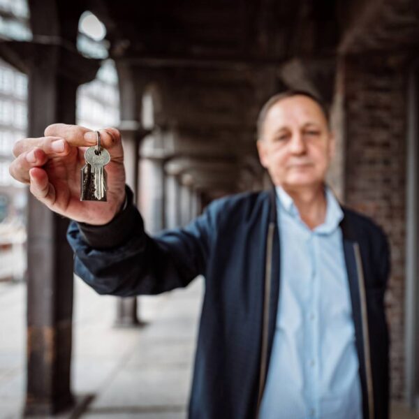 Ein Mann im blauen Hemd zeigt einen Wohnungsschlüssel in die Kamera