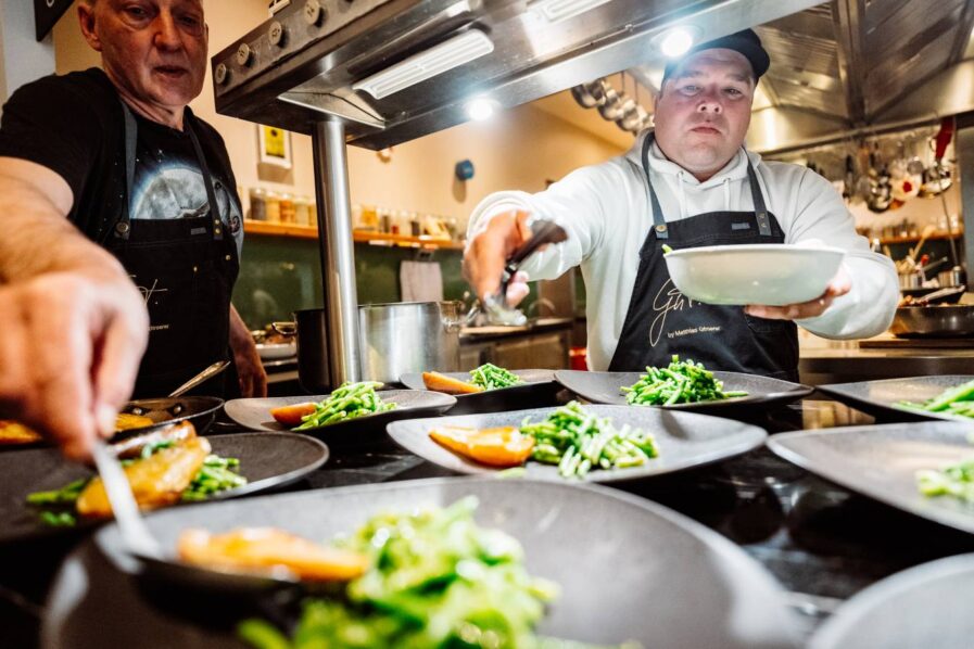 Ein Mann mit Schürze platziert Essen auf Tellern