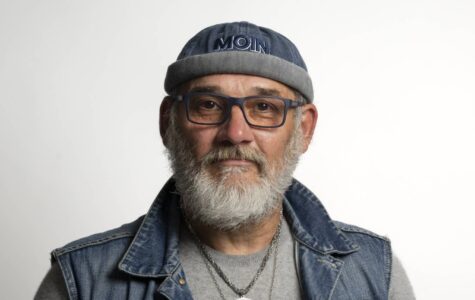 Ein Mann mit grauem Bart, Brille und einer Mütze mit der Aufschrift "Moin"