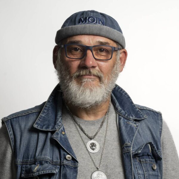 Ein Mann mit grauem Bart, Brille und einer Mütze mit der Aufschrift "Moin"