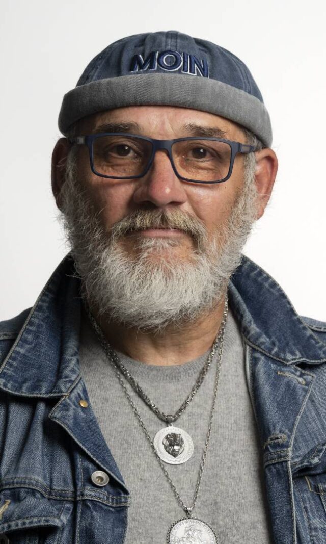 Ein Mann mit grauem Bart, Brille und einer Mütze mit der Aufschrift "Moin"