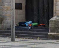 Schlafsäcke und Isomatten liegen auf einer Steintreppe vor einer Kirchentür
