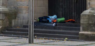 Schlafsäcke und Isomatten liegen auf einer Steintreppe vor einer Kirchentür